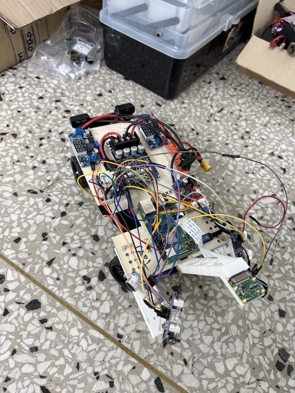 The self-driving car standing on a tiled floor, its wiring loom and sensor mast clearly visible.