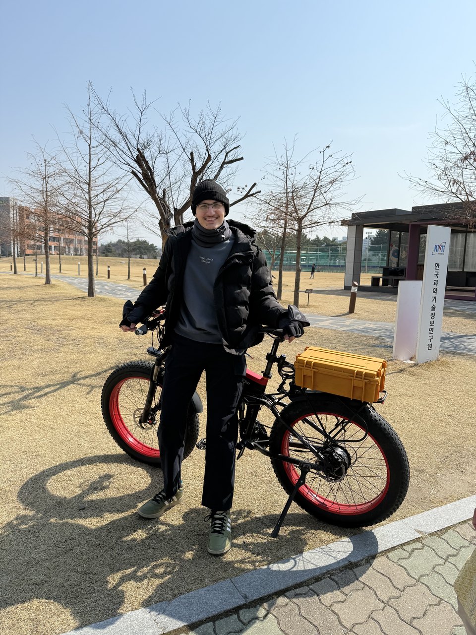 Abdullah standing with his fat-tyre e-bike on a campus path in winter.