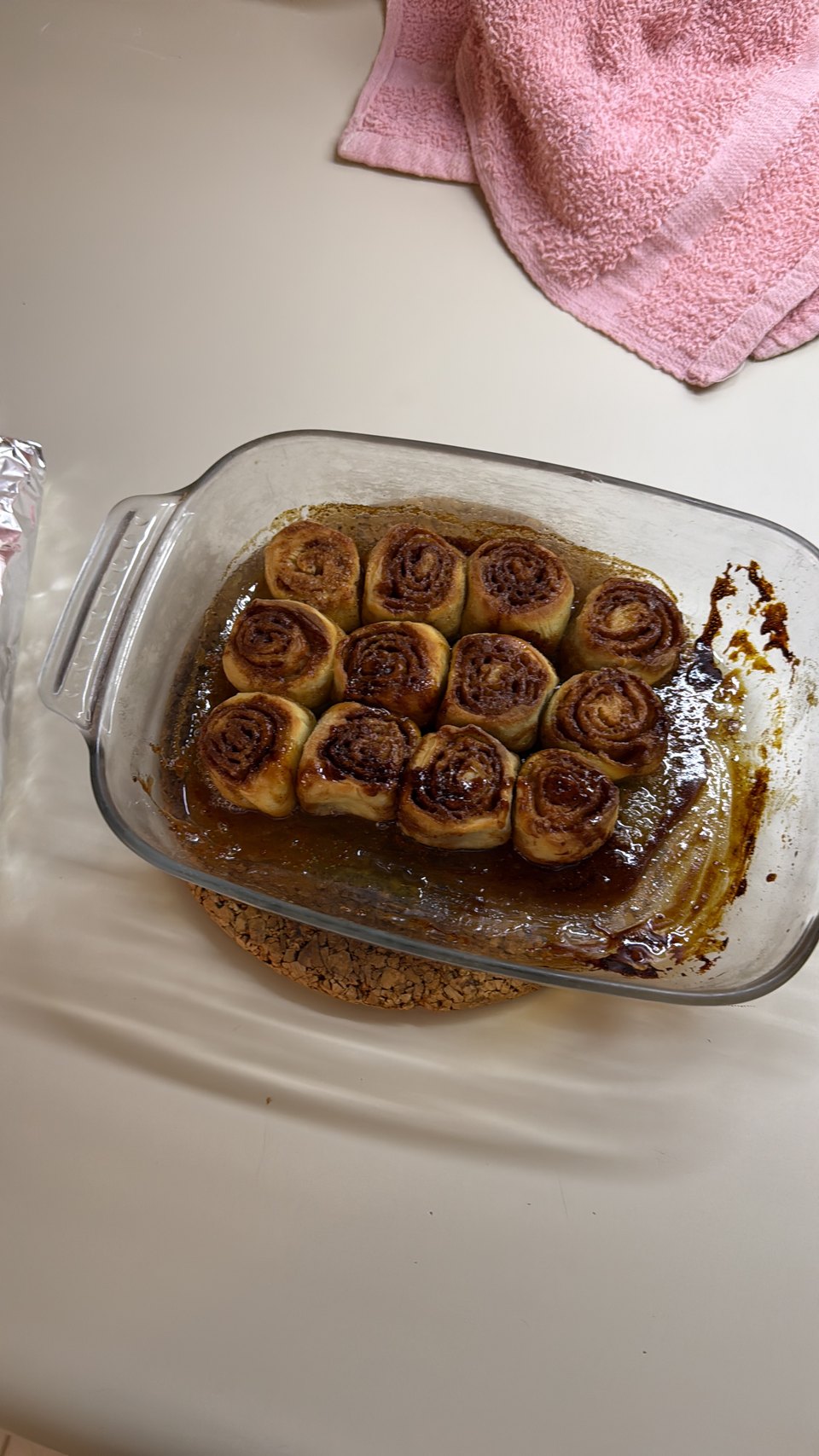 A glass dish of cinnamon rolls in caramel sauce, straight out of the oven.