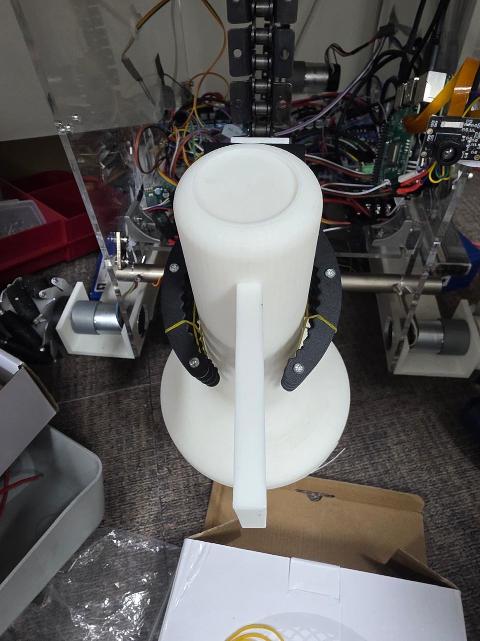 One of the robot's grippers clamped around a white competition flag, wiring and the chain drive visible behind it.