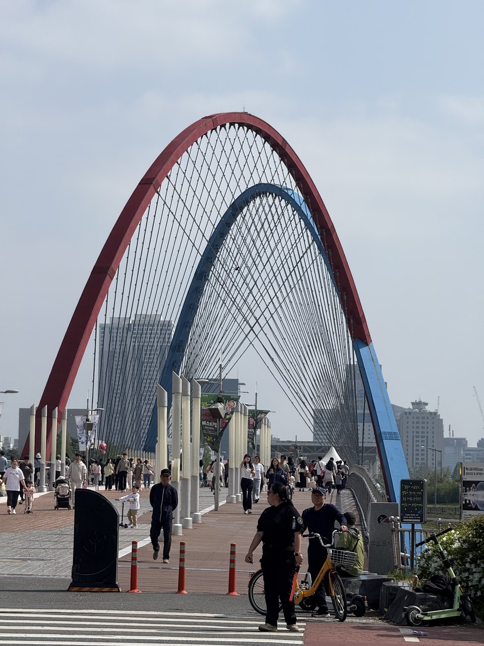 A red and blue arch bridge over a riverside path.