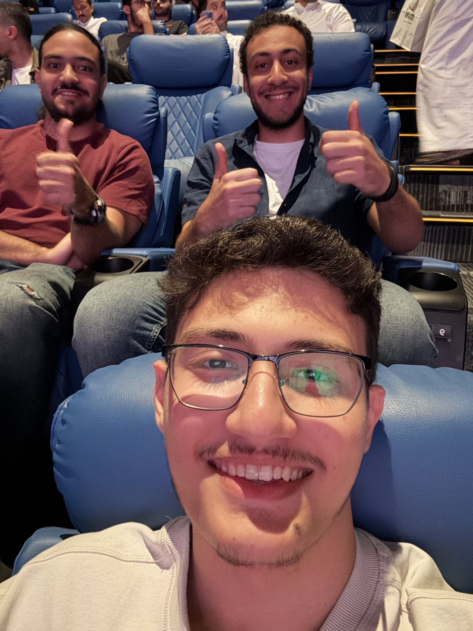 Abdullah and a friend grinning back at the camera from cinema seats.