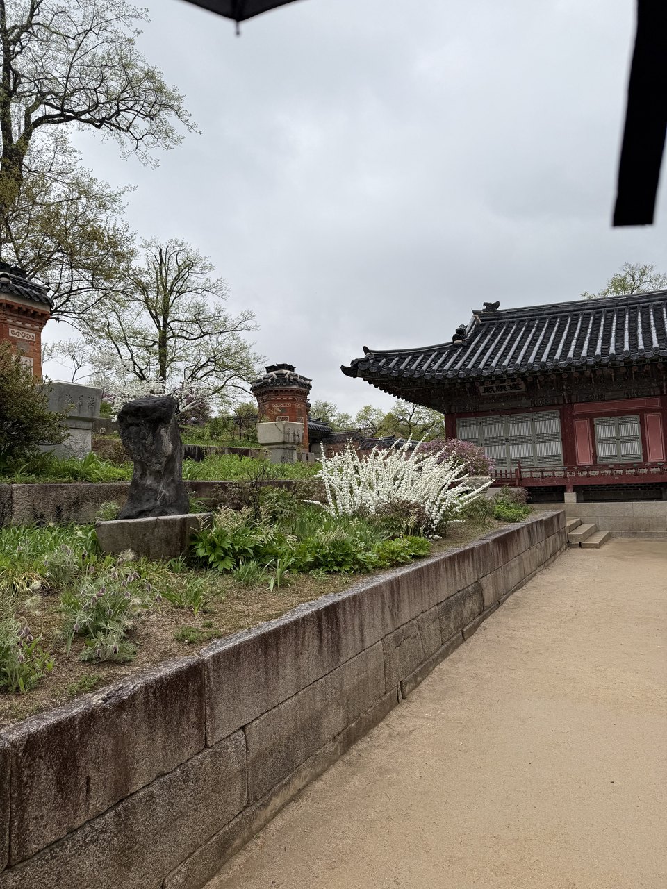 A Korean palace gate with visitors in hanbok crossing the courtyard.
