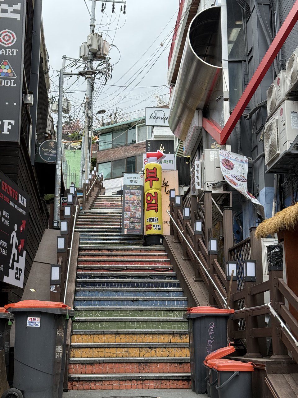 A steep street stairway painted in rainbow stripes and lined with shopfronts.