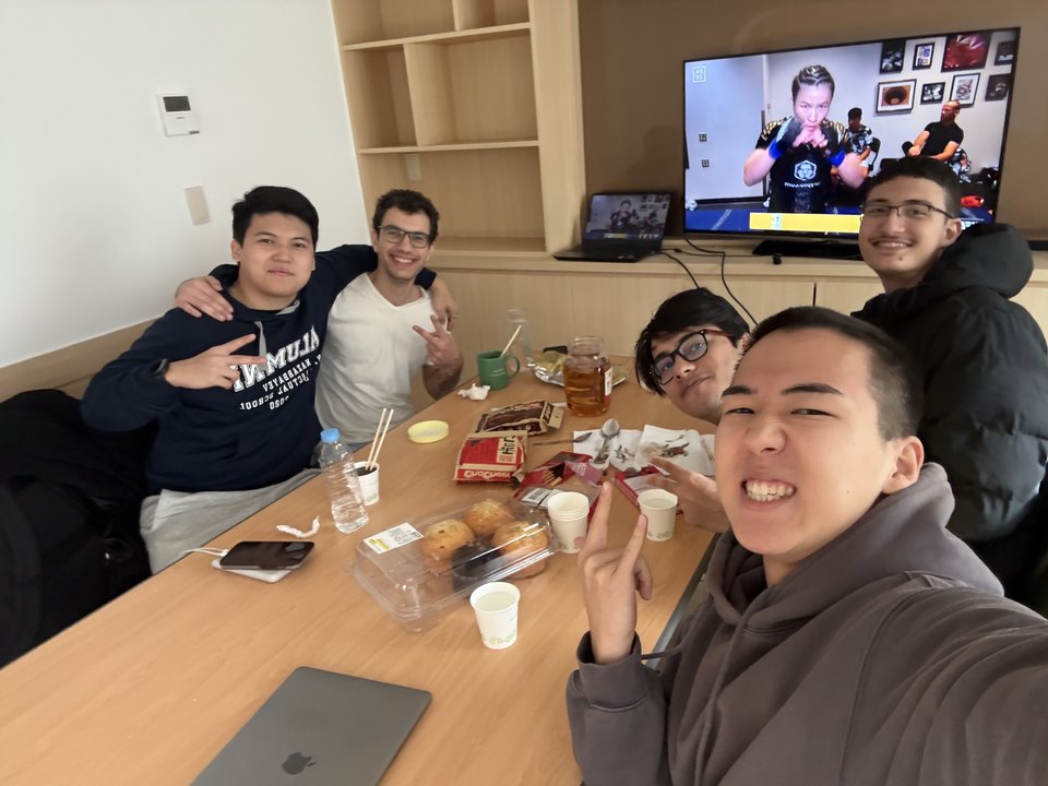 Friends crowded around a table of drinks and snacks.